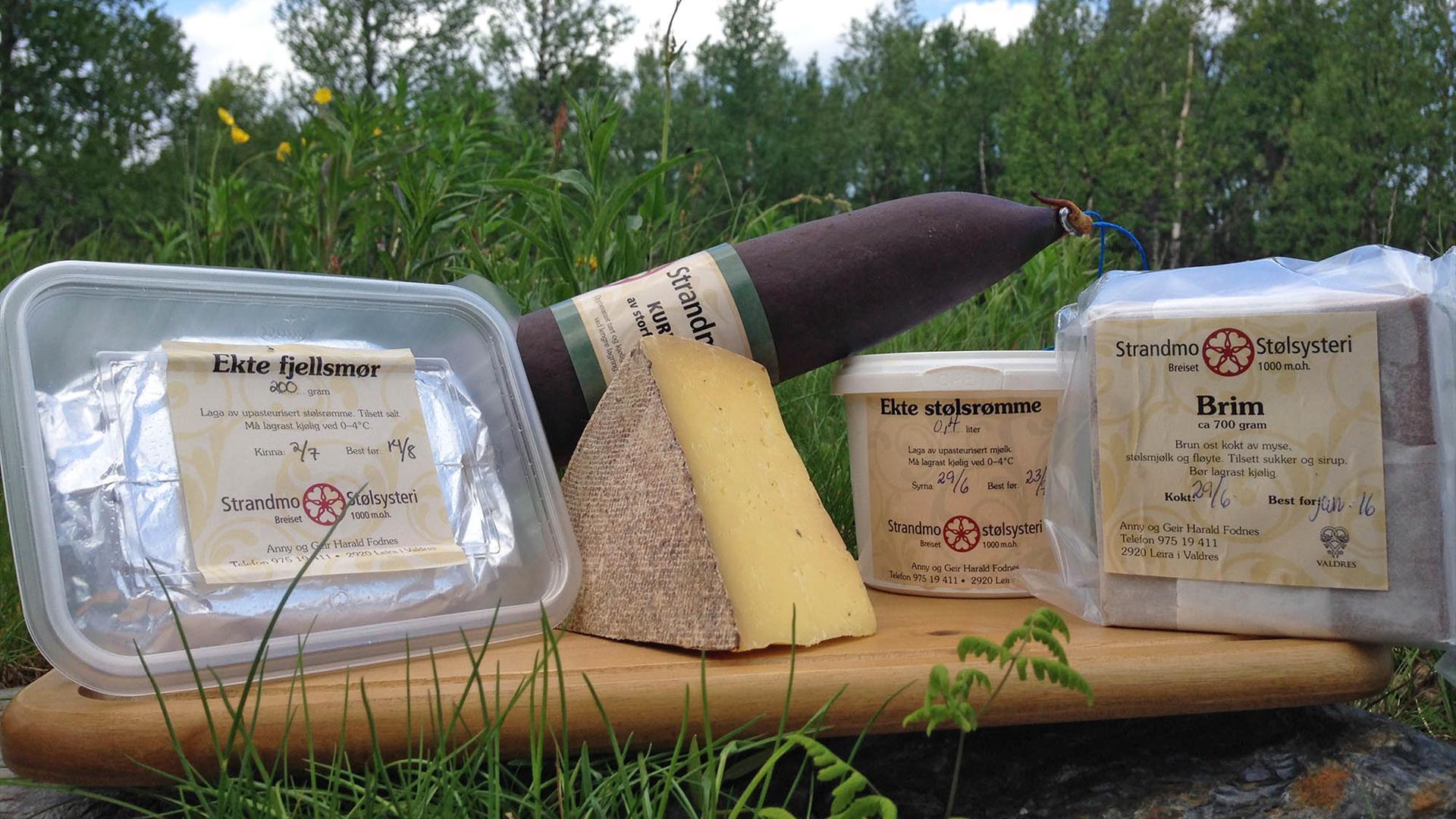 Trefjøl med diverse oster ute på en sommereng