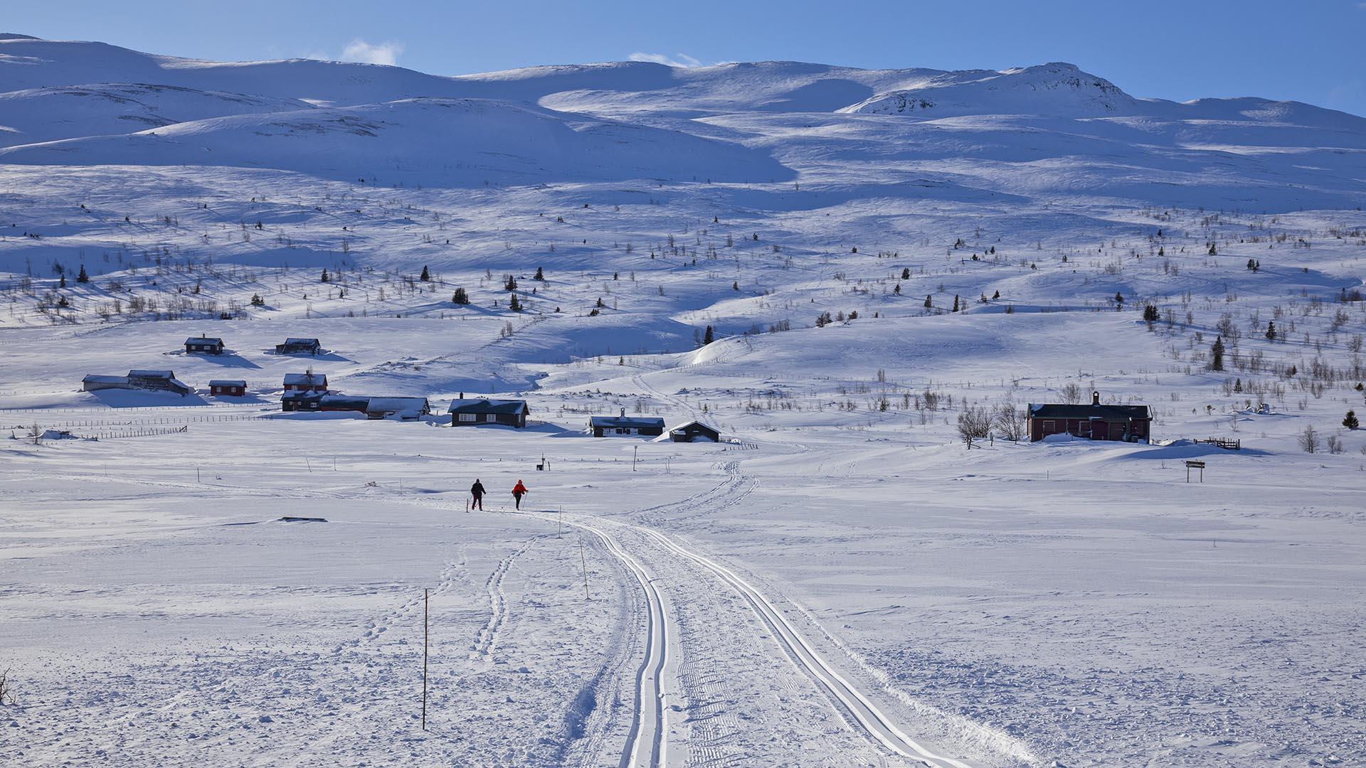 Skiløyper i forgrunnen, med hytteområde og fjell i bakgrunnen