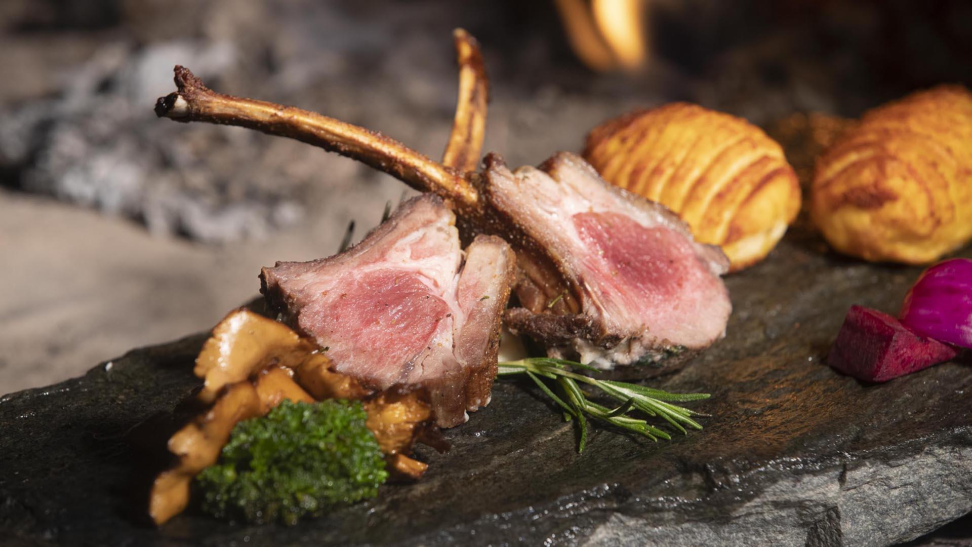 Lambracks served on a plate of slate with hasselback potatoes on the side