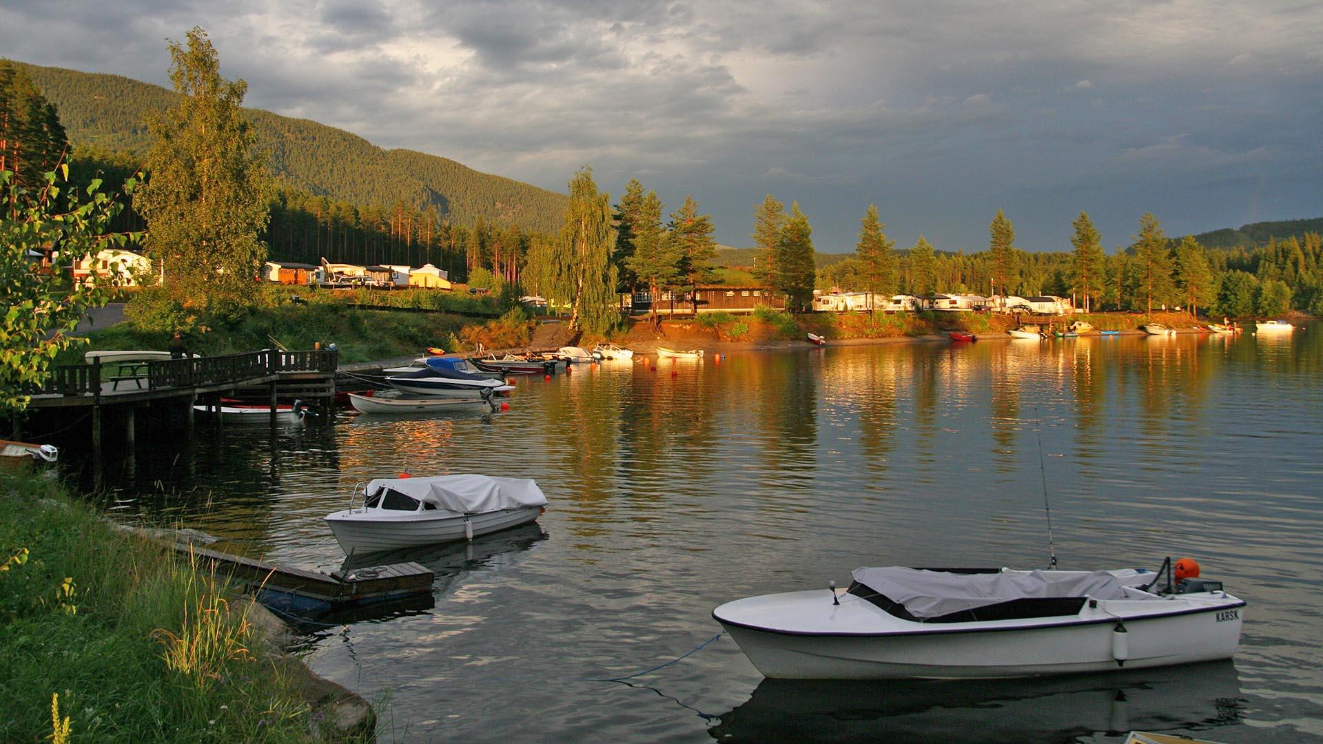 Bilde av vannet nedenfor Aurdal Fjordcamping, der det ligger 4 båter og vaker i vannet.