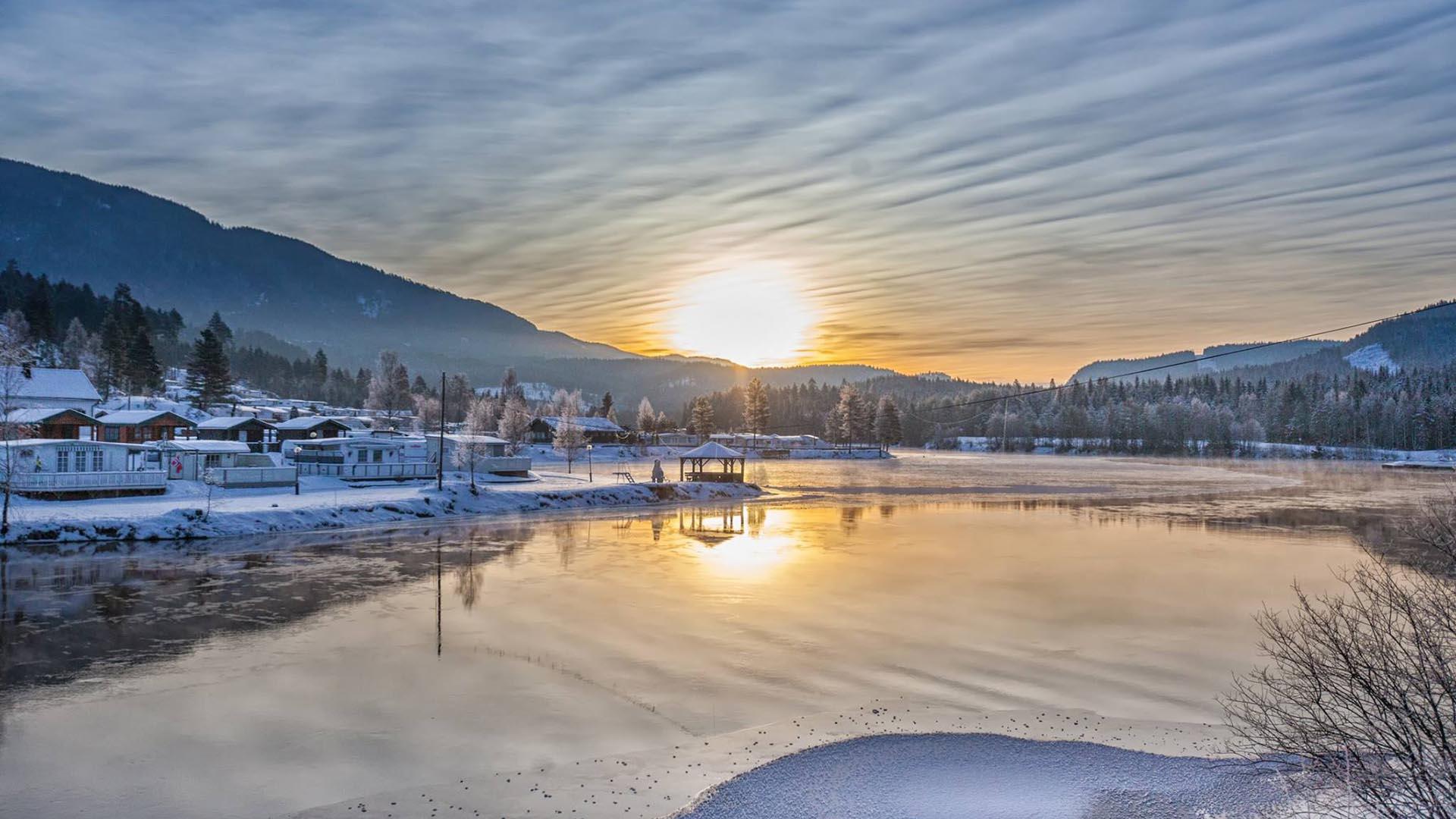 The low winter sun in the middle of the picture gives a beatiful backdrop for this winterday at Aurdal fjordcamping with the lake in the foreground.