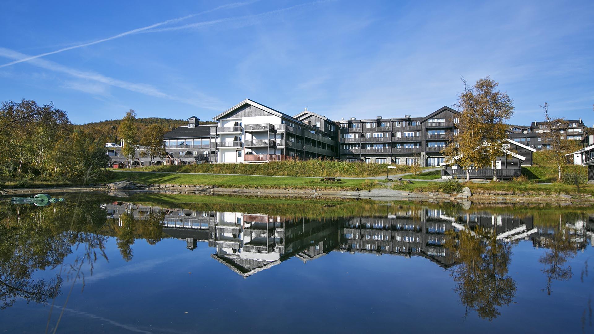 Beitostølen Apartment hotel a summers day, with a small pond in front of it.