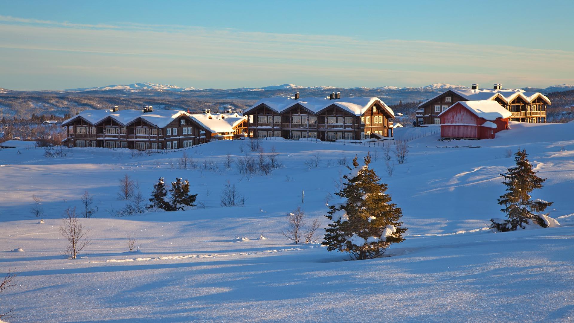 Vinterlandskap på fjellet med tre leilghetsbygg i vintersola