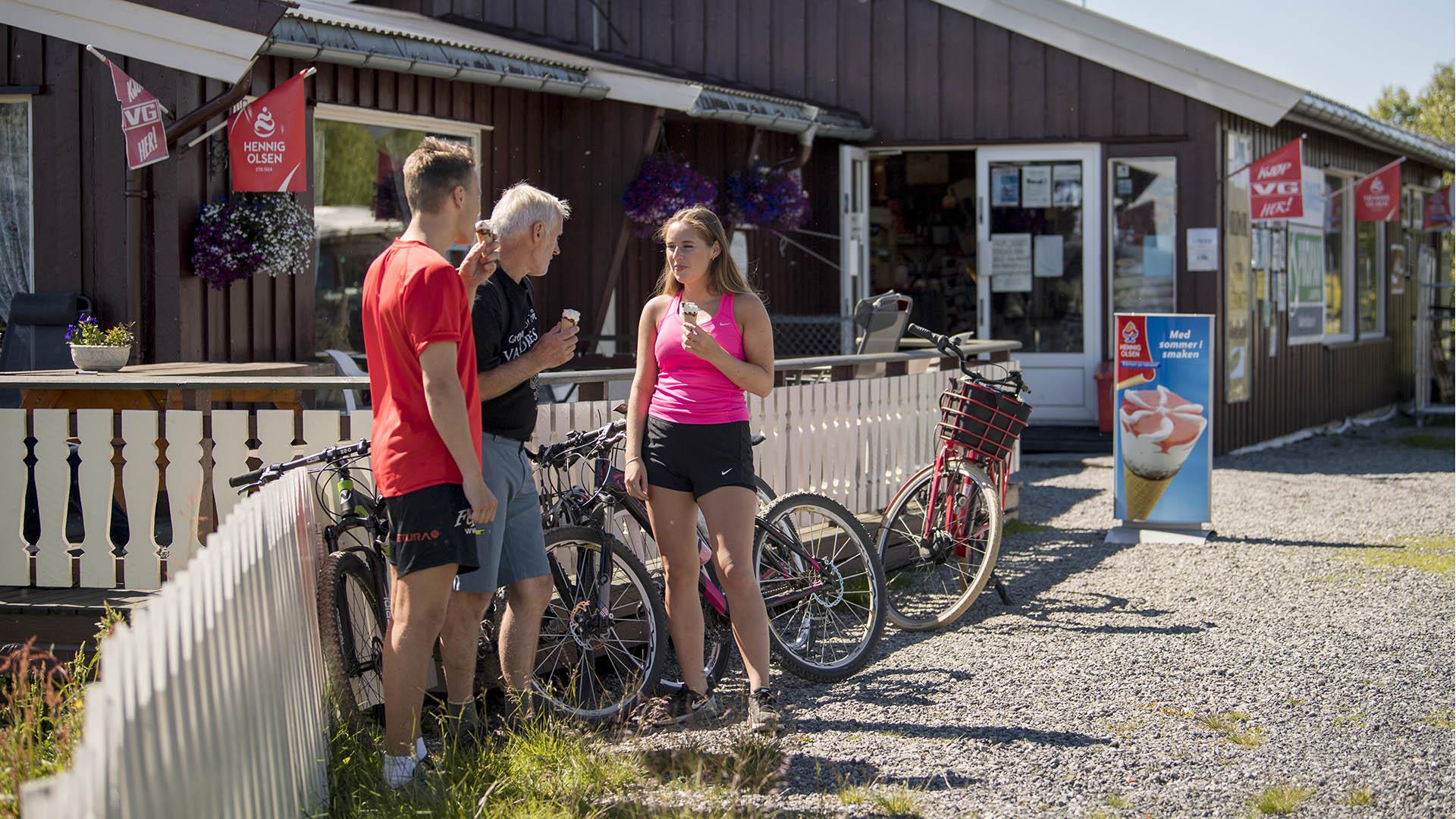 Syklister spiser is foran en kolonialbutikk