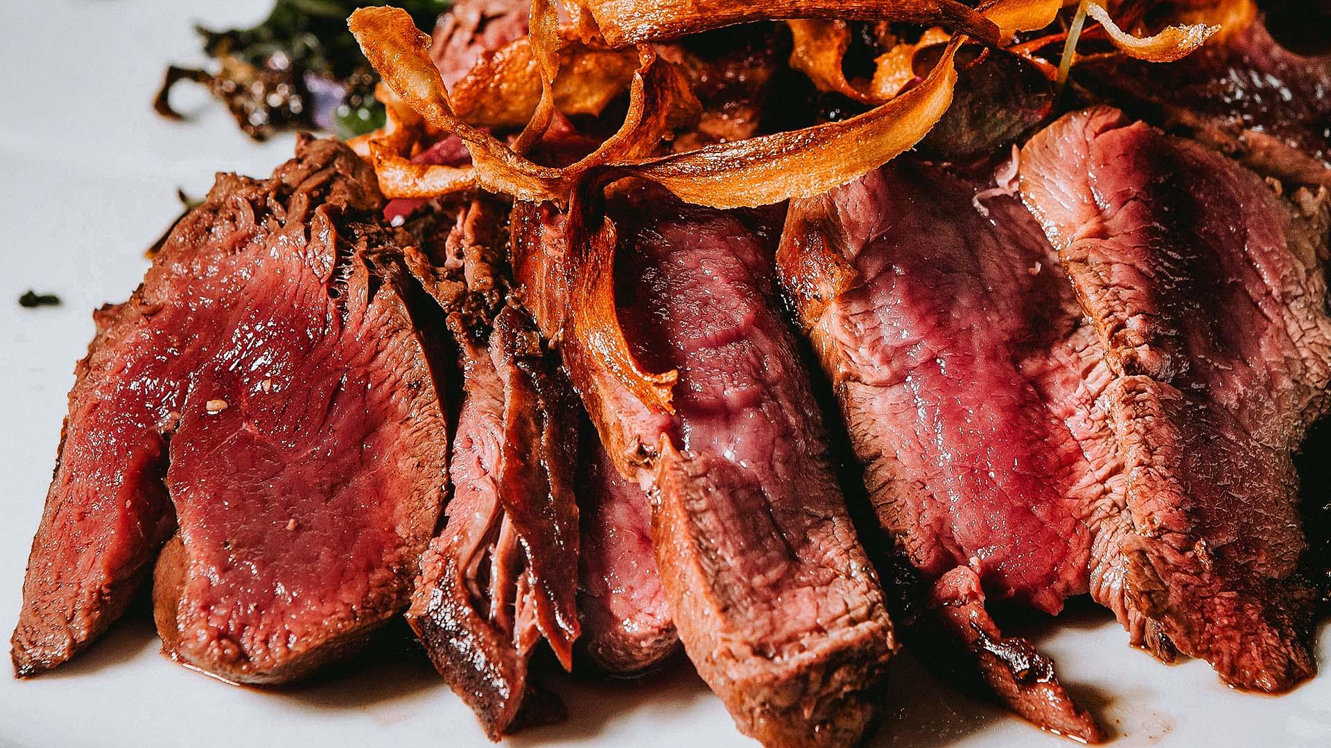 Medium rare cooked morat cut on a plate with crispy root vegetables on the side.