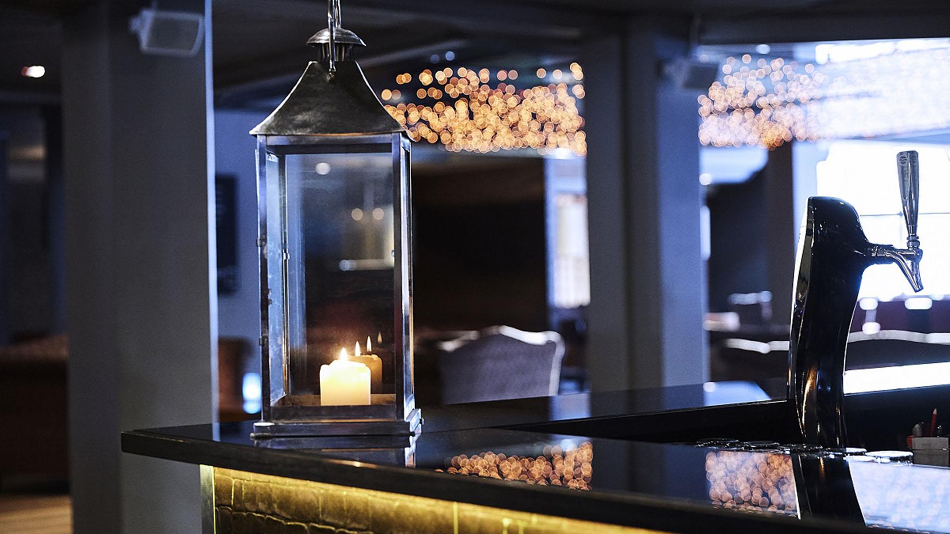 Bar disc on a hotel with a lit candle in a lantern in front.