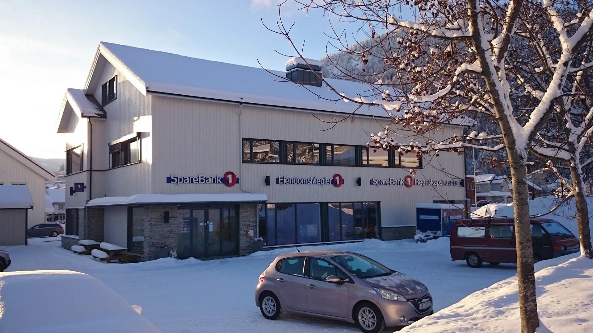 Et hvit trebygg som huser Sparebank1 Valdres Hallingdal i morgensola en vintermorgen.