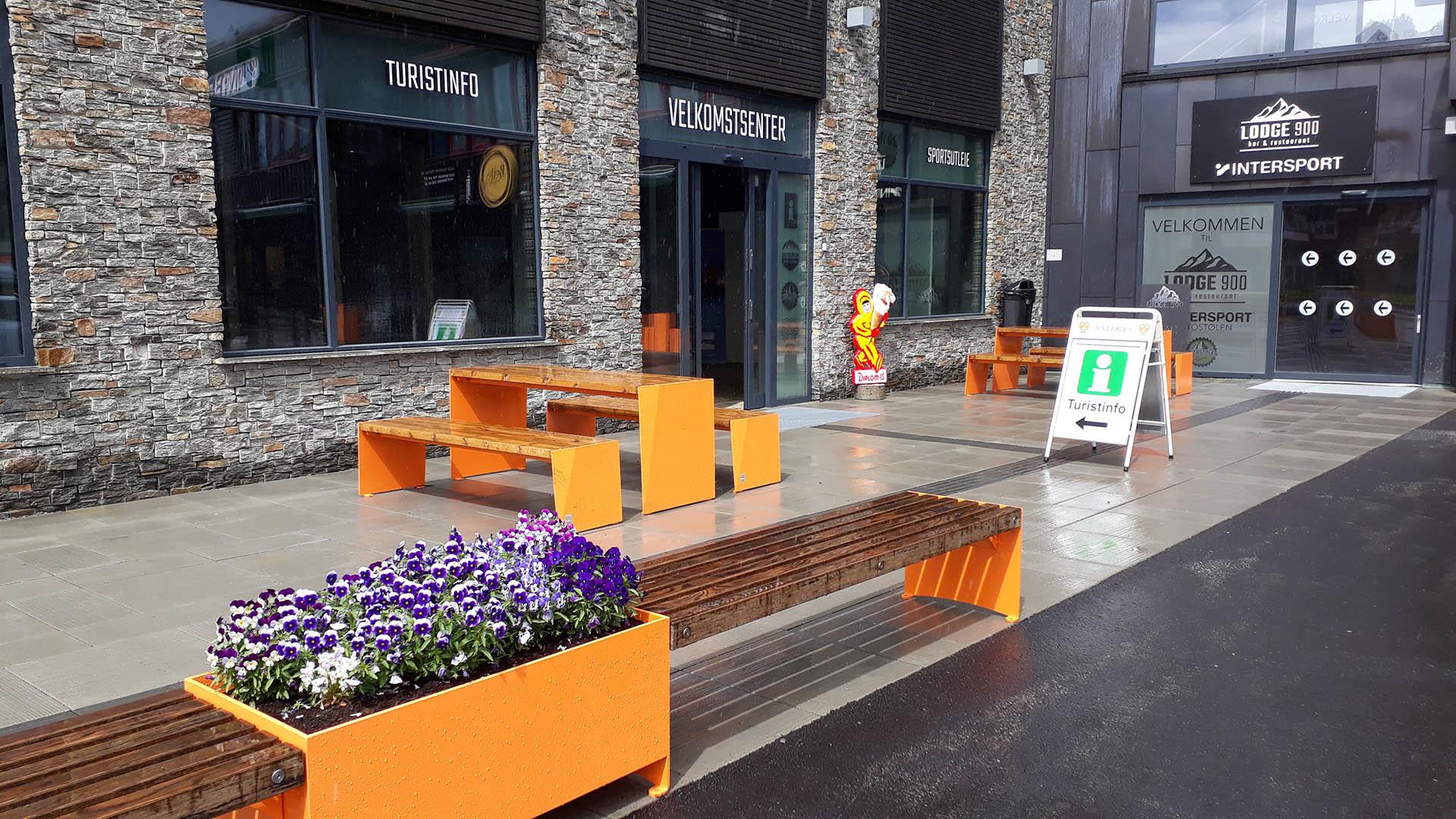 Benker og bord i moderne design i tre og stål med blomsterkasse utenfor Beitostølen Turistkontor.