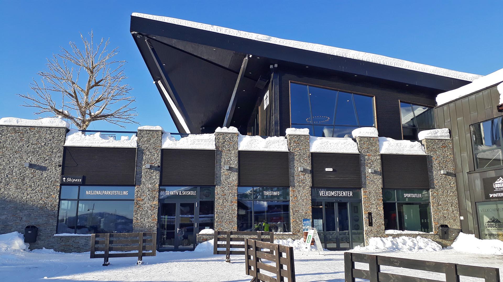 A modern building in wood and stone with a roof terrace a sunny winter's day