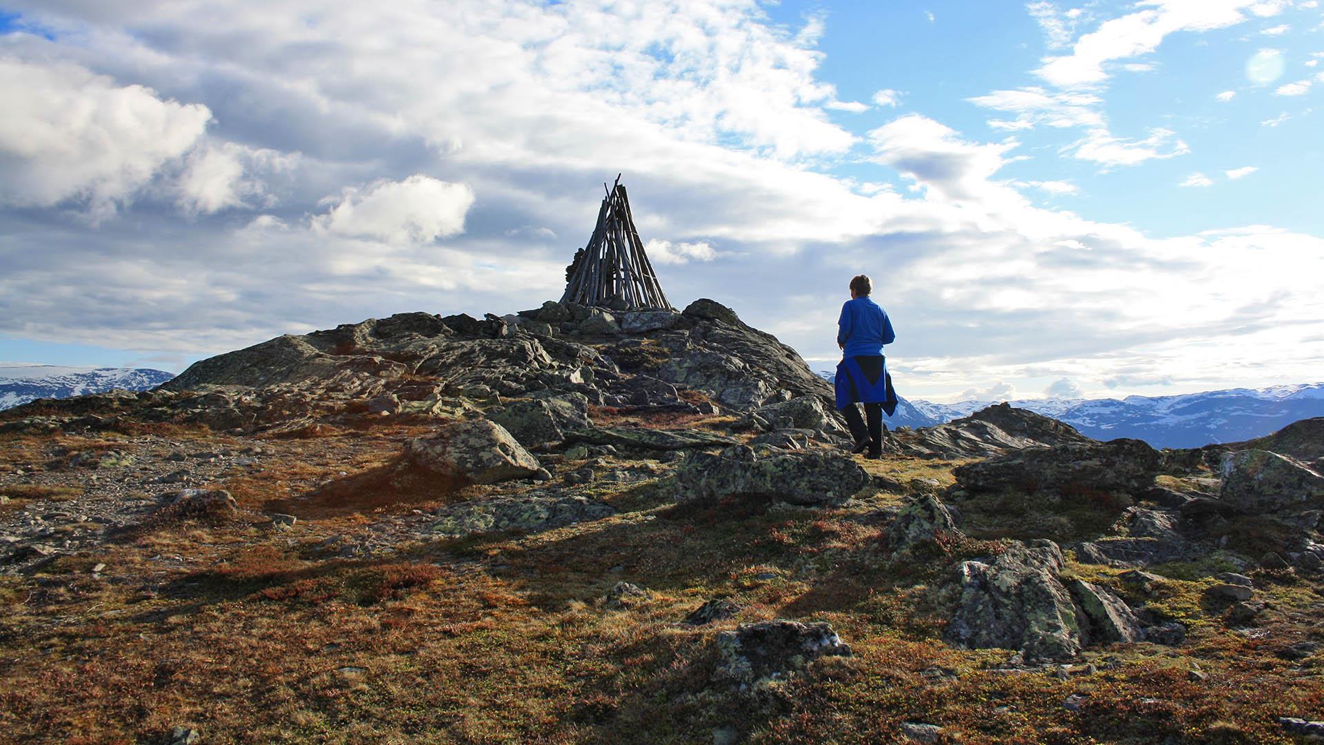 Person on his way to a mountain top where a beacon stands.