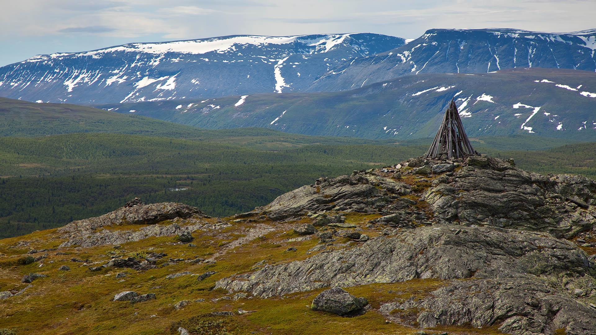 In front a mountain top with a beacon, behind plains that ends up in mountains.