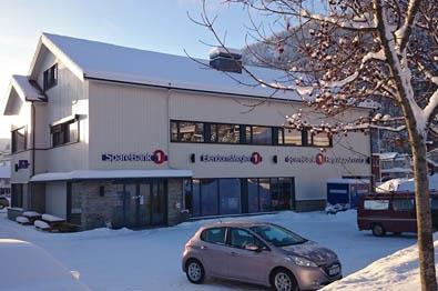 Ein weißes Holzgebäude mit einer Bankfiliale an einem sonnigen Wintermorgen.