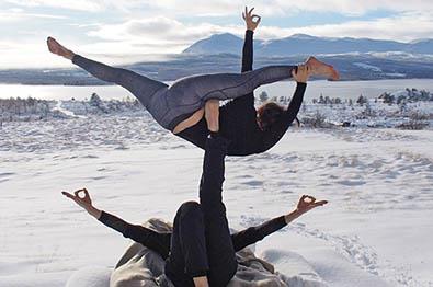 Zwei Personen machen Yoga im Freien in den Bergen im Schnee.