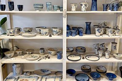 Hylle med håndlaget keramikk i beige- og blåtoner