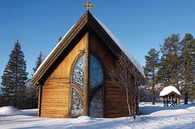 Small wooden chapel with glass mosaik in the snow