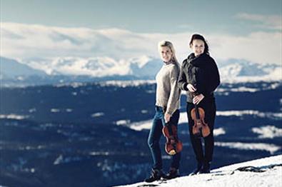Promobilde for Hemsingfestivalen med Ragnhild og Eldbjørg på toppen av fjellet, og med majestetisk bakgrunn.