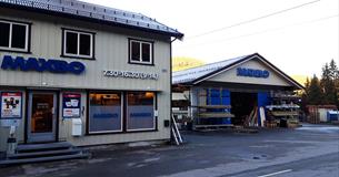 Byggevareforretning med varelager fra utsiden. Bygget er kledd i lyst trepanel.