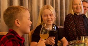 Barn og voksne som koser seg rundt middagsbordet