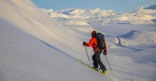 Person on the way upwards with randonee skis, great view over the snow covered mountain landscape.