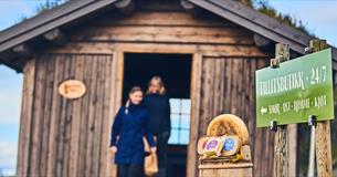 Skilt som sier: Tillitsbutikk 24/7 med utsalget i bakgrunn.