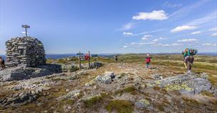 Eine große Steinwarte und Wanderer auf dem höchsten Punkt des Bjørgovarden