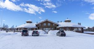 Trebygg med i snø med vinterbrøytet parkeringsplass
