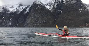 kajakk på en fjord med snødekte fjell bakenfor