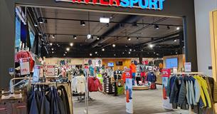 The entrance to Intersport Leira, racks with outdoor jackets and the logo over the entrance.