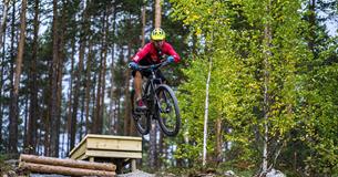 A cyclist jumping over an obstacle in  the terrain cycling area at Leira
