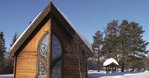 Det lille, fine Lyskapellet på Beitostølen utenfra på vinteren med snø på bakken.
