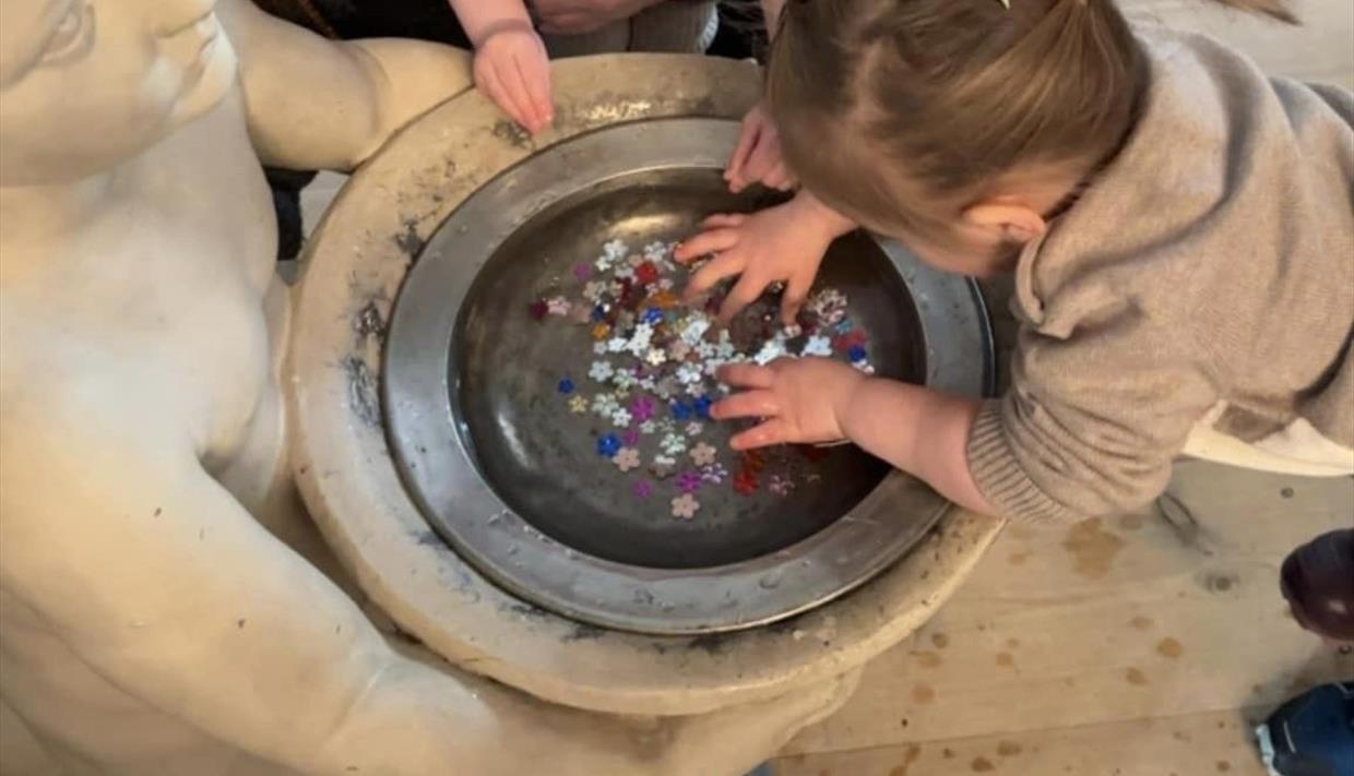 Barn ser på perler i døpefonten i Ulnes kyrkje