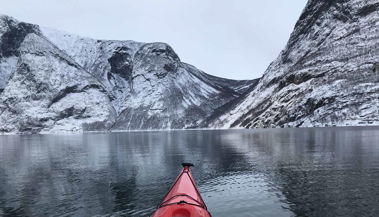 Kajakk med høye snødekte fjell foran
