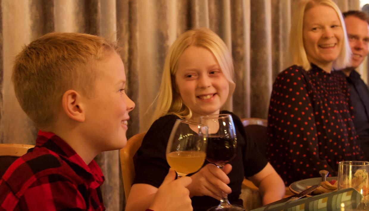 Barn og voksne som koser seg rundt middagsbordet