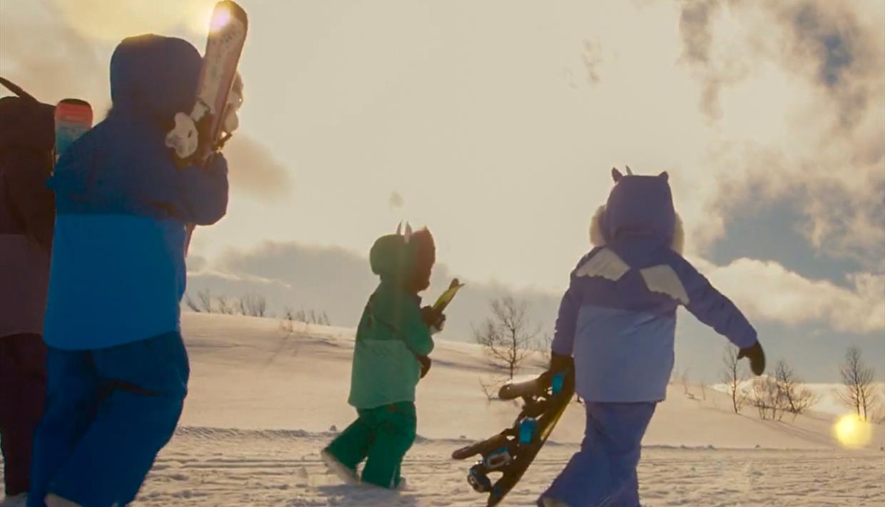 Barn som går i vinterlig landskap med ski og truger