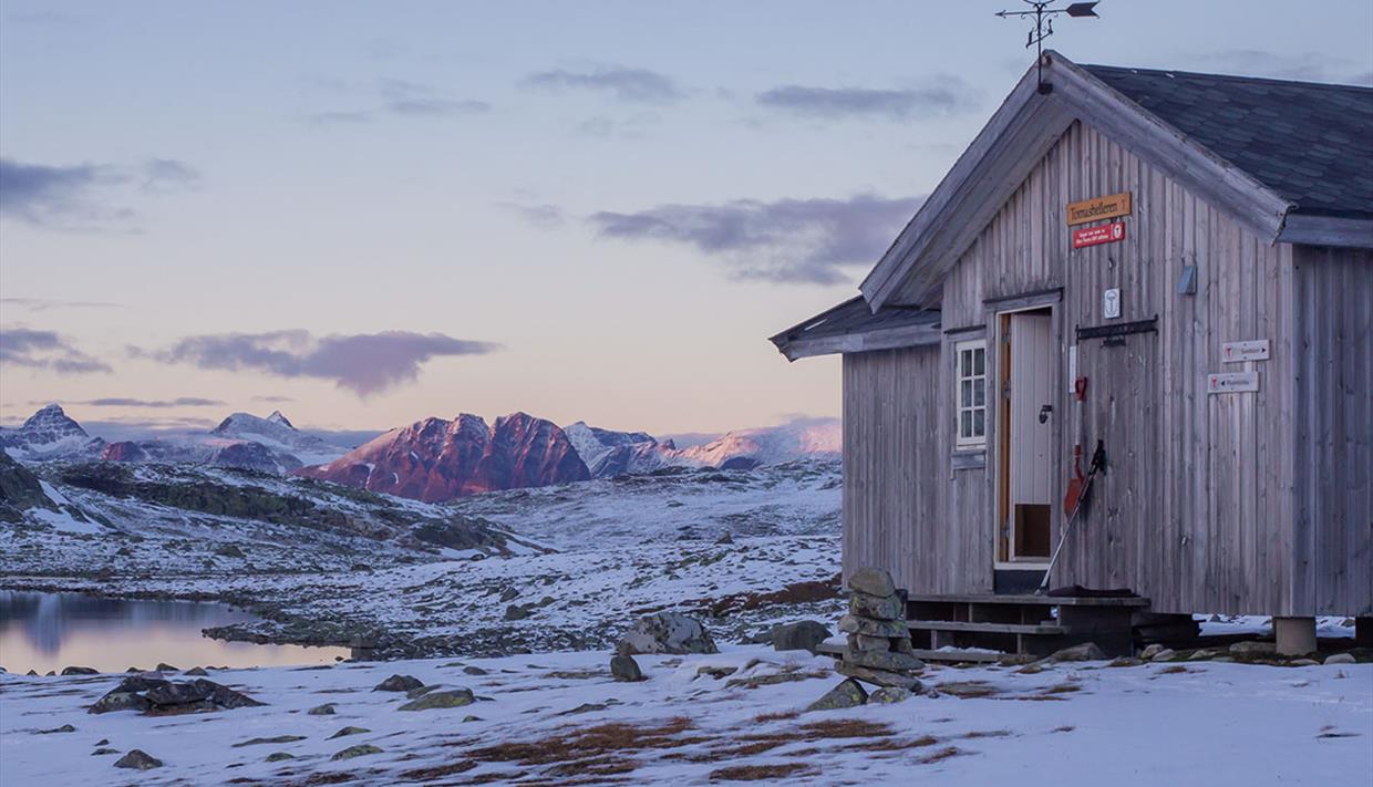 Tomashelleren en flott høstdag. Snødekte fjell i bakgrunnen.