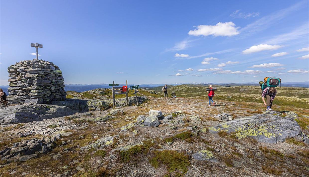 A large stone cairn and people hiking on Bjørgovarden