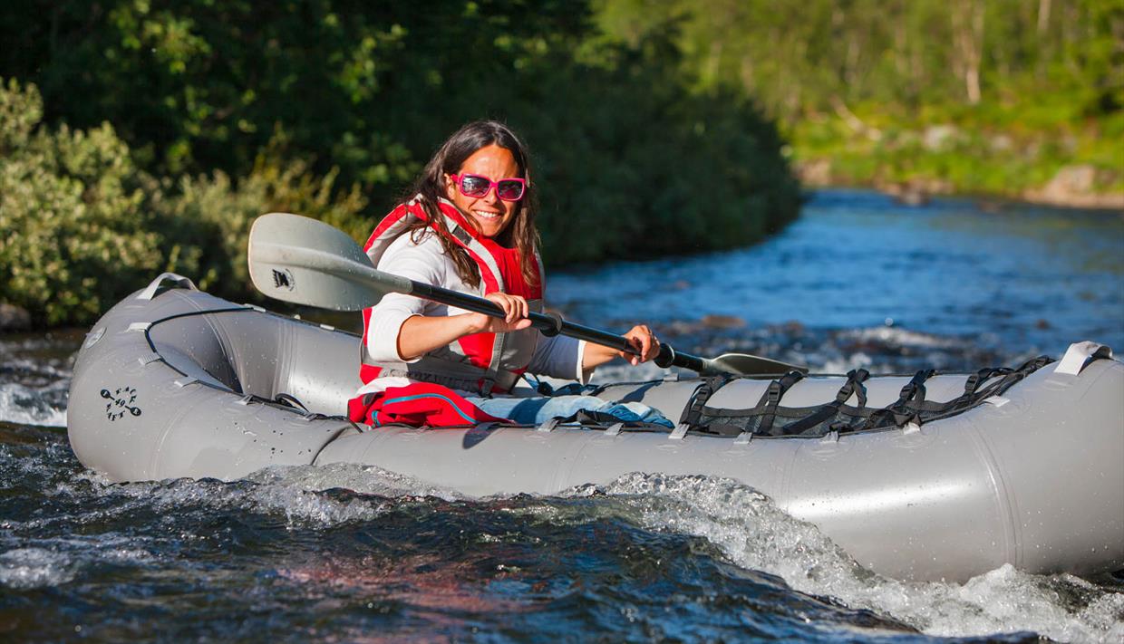 Eine Frau in einem Packraft in einem Fluss