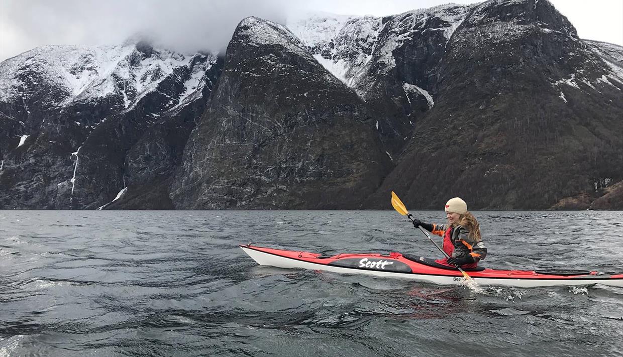 kajakk på en fjord med snødekte fjell bakenfor