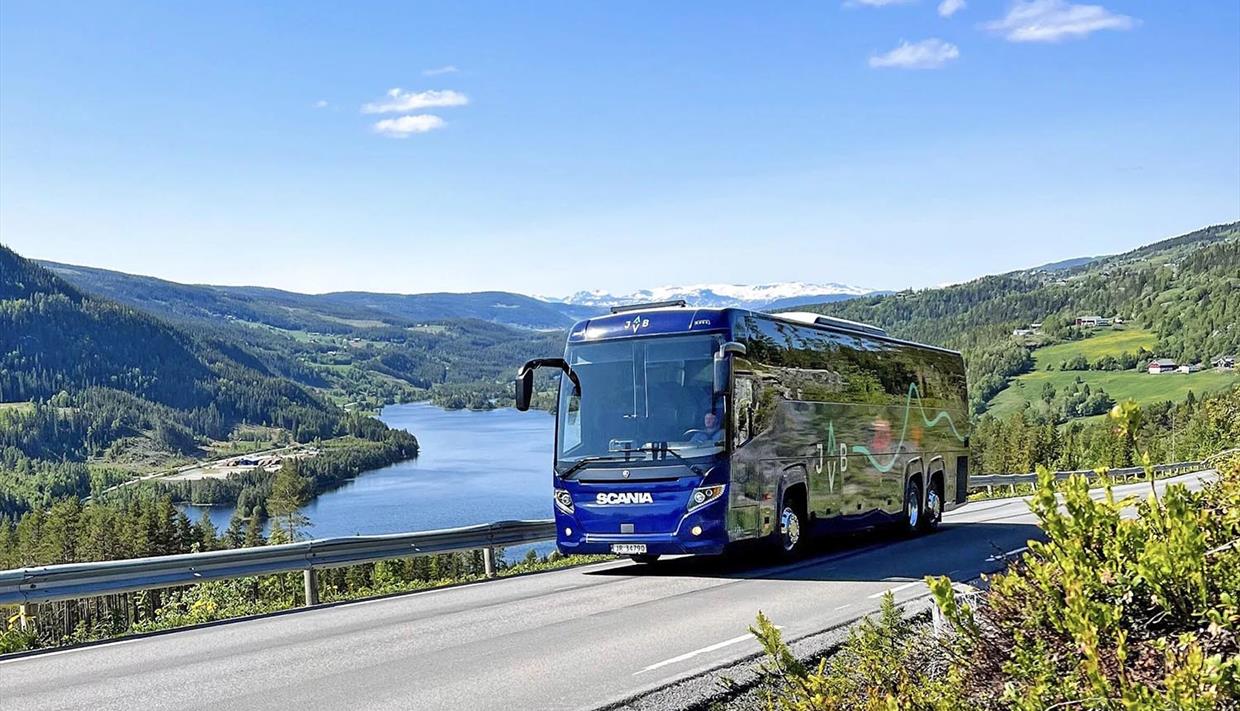 Buss på vei med fin utsikt mot vann og fjell