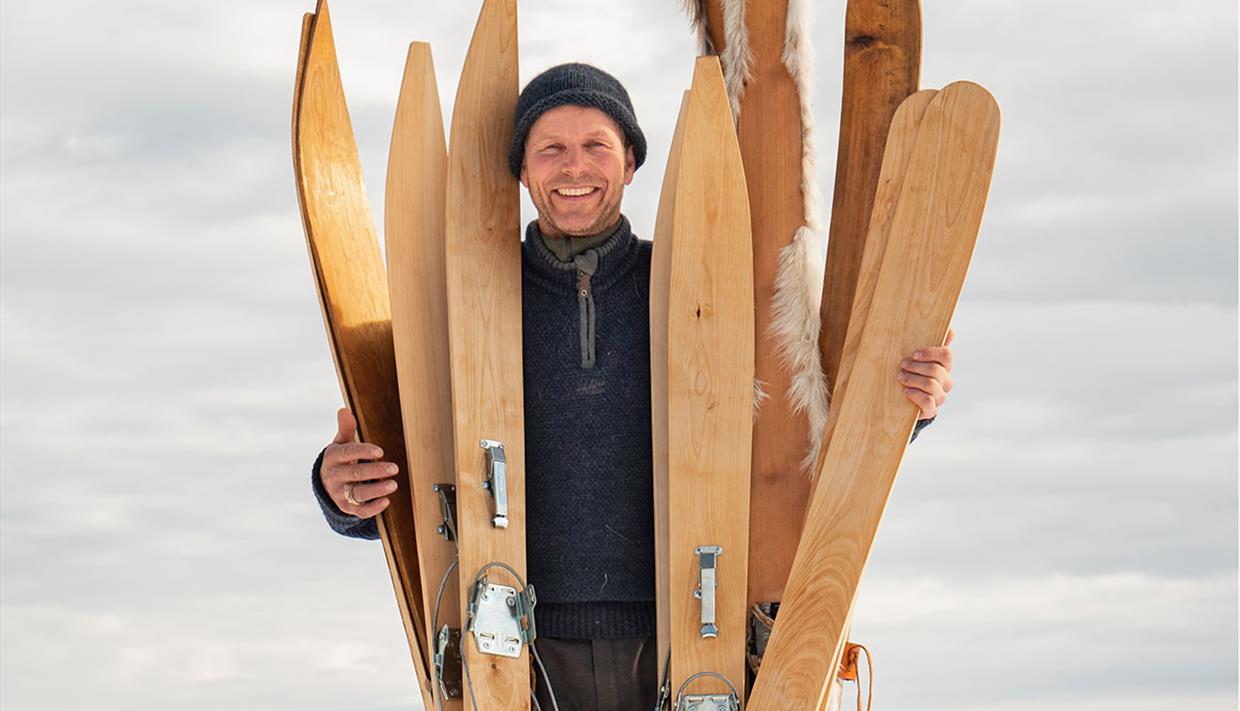 Skimaker'n poserer med flere av skiene sine