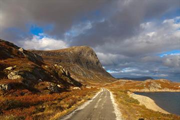 Autumn colours along Bygdisheimvegen with the mountain Synshorn in the background. The gravel road is flat and easy to cycle on.
