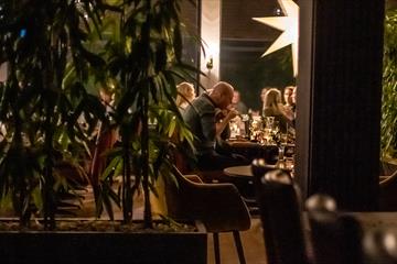 Stemningsbilde hvor en gjeng sitter og spiser middag med julestjerne i bakgrunn.