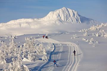 skiløyper i løype på snaufjellet med utsikt til fjell