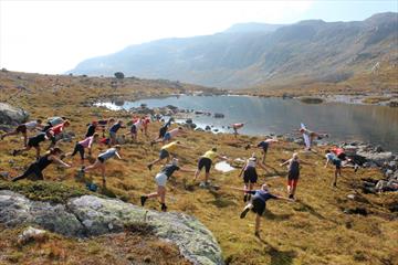 Yoga på fjellet med over 30 deltakere. Fjellvann i bakgrunn.