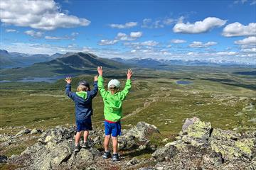 Children enjoy a great view over open mountain terrain with lakes and mountains.
