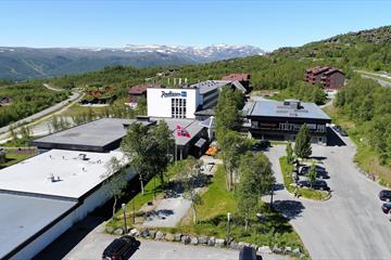 Hotellet sett ovenfra, med flott utsikt mot Jotunheimen i bakgrunnen.