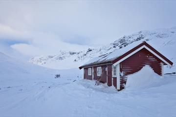 Small mountain hut during winter with skies against the wall