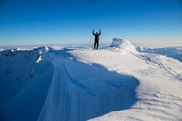 Skiløper på fjelltopp med skavel og stup