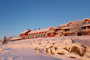 A red wooden hotel in snowclad landscape and warm winter light