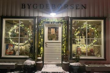 Landhandel inngang med snø på trappa og julelys i vinduene
